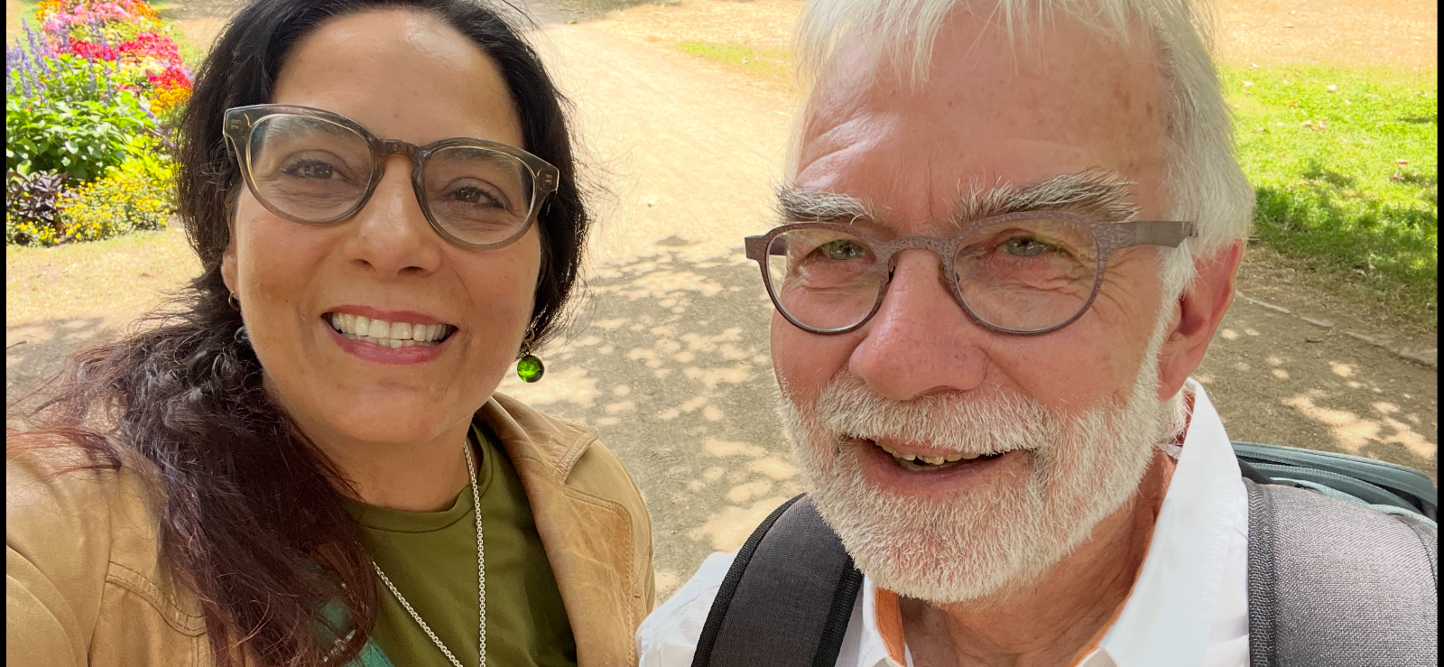 Das Foto zeigt Giovanna Lo Presti und Karlheinz Pape. Sie stehen
draußen im Grünen und lächeln in die Kamera. Die Sonne scheint, im
Hintergrund sieht man Blumen und einen
Weg.